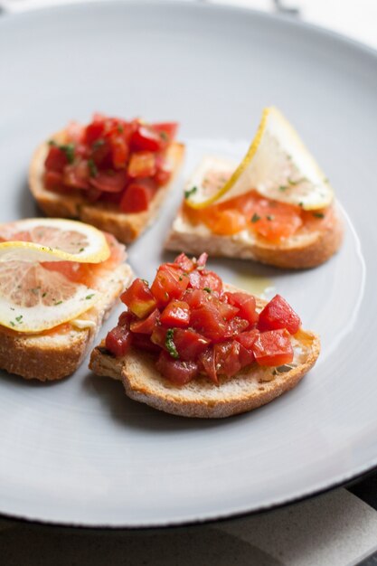 Plato de picatostes con salmón y verduras decoradas con rodajas de limón.