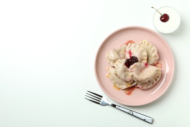 Plato con pierogi con cereza sobre fondo blanco.