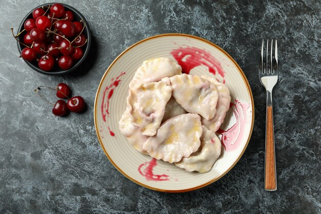 Plato con pierogi con cereza sobre fondo negro ahumado