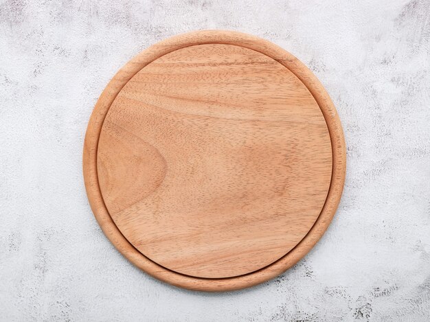 Plato de pizza de madera vacía sobre hormigón blanco. Tablero de pizza sobre fondo de hormigón blanco plano y copie el espacio.