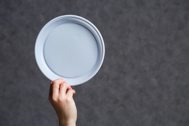 Plato de plástico blanco desechable sobre un fondo oscuro