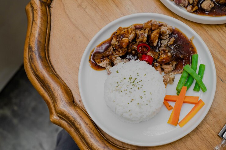 Un plato de pollo a la pimienta negra con arroz y judías verdes adicionales y zanahoria