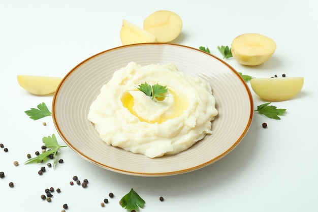 Plato de puré de patatas e ingredientes sobre fondo blanco.