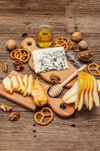 Plato de queso antipasti con queso ahumado y azul, galletas, miel, nueces y pera madura. Receta de merienda tradicional