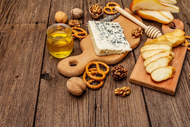 Plato de queso antipasti con queso ahumado y azul, galletas, miel, nueces y pera madura