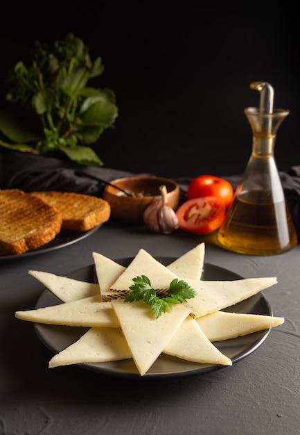 Plato de queso en lonchas. mesa rústica oscura