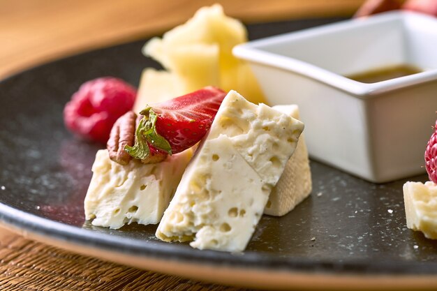 Plato de queso con miel, nueces y fresas. Vista cercana de Camembert