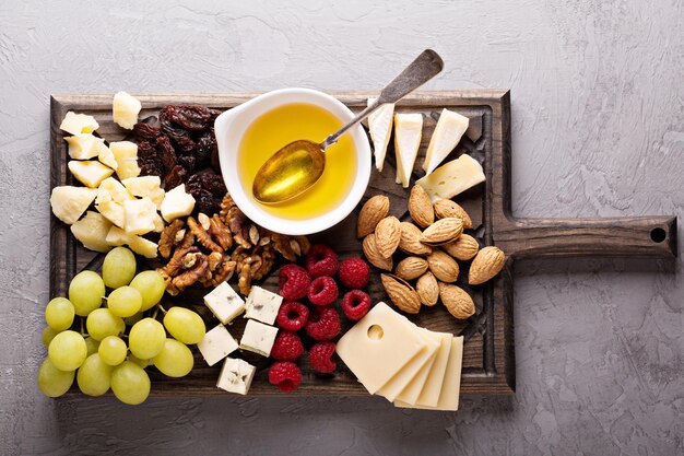 Foto plato de queso con nueces, miel y uvas