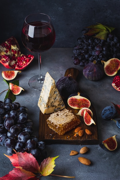 Foto plato de queso con queso dorblu, uvas, higos, salsas y vino tinto