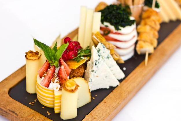 Plato de queso: roquefort con moho azul, queso cheddar, queso ahumado, mozzarella sobre una tabla de madera.