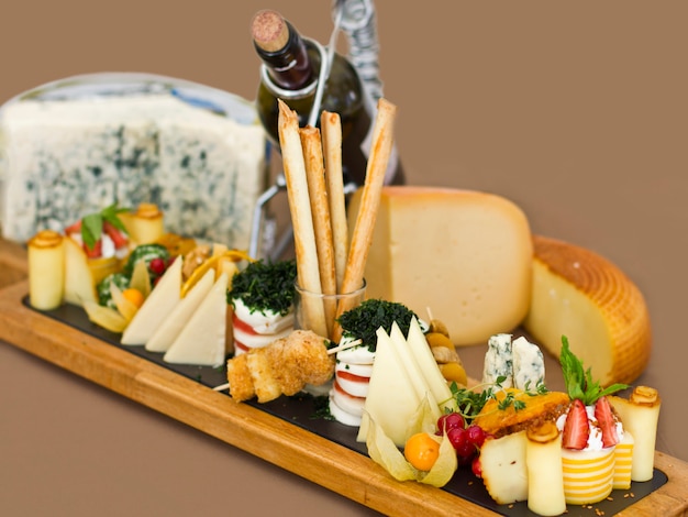 Plato de queso: roquefort con moho azul, queso cheddar, queso ahumado, mozzarella sobre una tabla de madera.