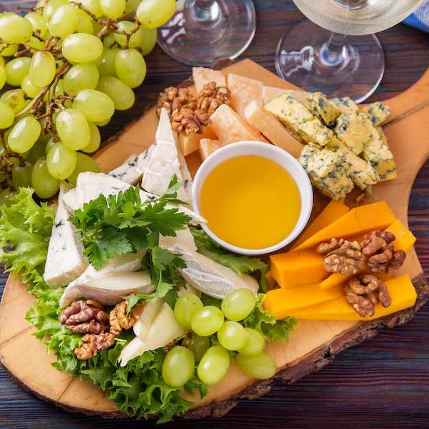 Plato de queso servido con vino blanco, uva y nueces.