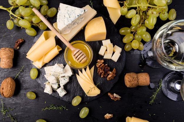 Plato de queso. Surtido de queso con nueces, pan y miel en placa de pizarra de piedra.