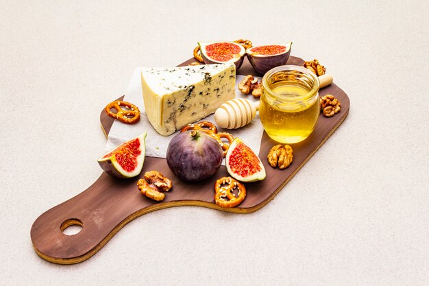 Plato de queso (tabla) con queso azul, miel, nueces, higos, pretzels