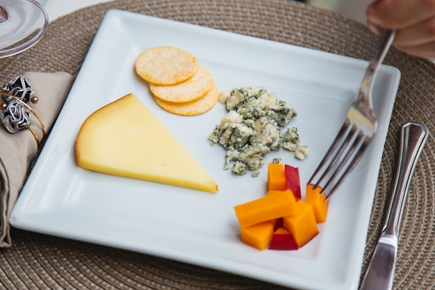 Plato de queso con variedad de aperitivos en la mesa.