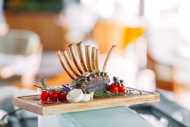 Plato Rack de cordero con tomates en una bandeja de madera.