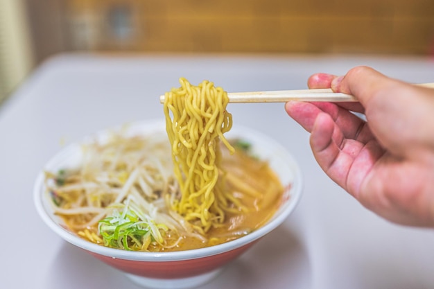 Un plato de ramen con palillos y un plato de fideos