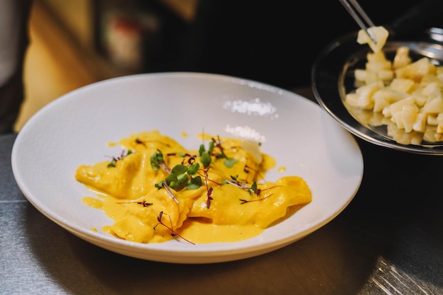 Un plato de raviolis con un plato de puré de patatas al lado