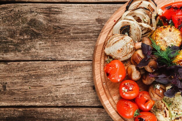 Foto plato redondo con verduras a la plancha sobre mesa de madera rústica, vista superior. espacio libre para texto.