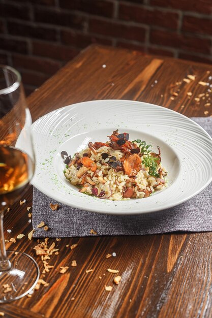 Foto plato de risotto en un plato blanco y una copa de vino oscuro y de mal humor nuevo