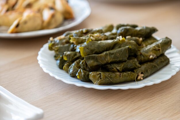 Foto plato de rollos de uva en una mesa de madera desde arriba con sambousek y qatayef