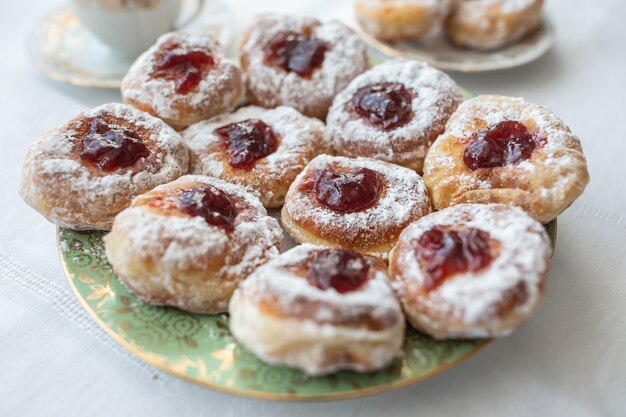 Un plato de rosquillas rellenas de mermelada y cubiertas de azúcar.