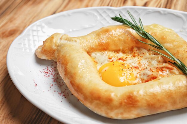Plato con sabroso Adzharian khachapuri en un primer plano de mesa de madera
