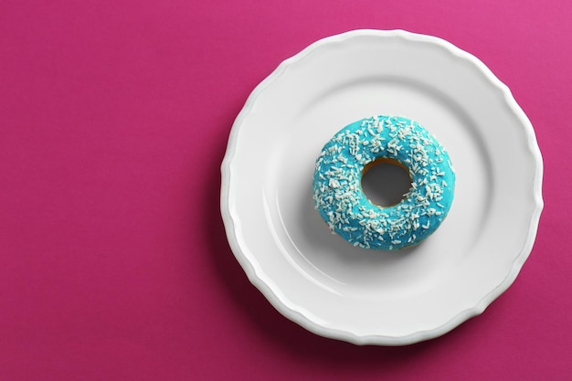 Plato con sabroso donut glaseado sobre fondo de color