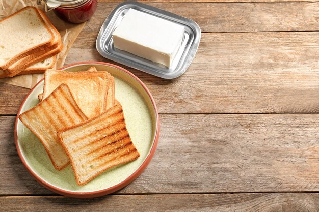 Plato con sabroso pan tostado sobre mesa de madera