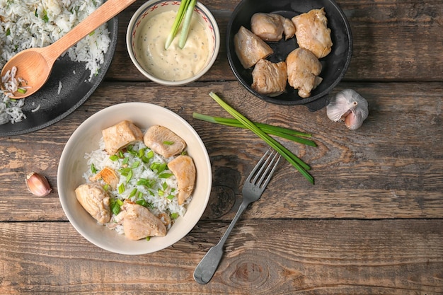 Plato con sabroso pollo y arroz en mesa de madera