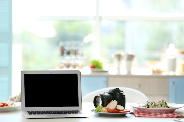 Plato sabroso portátil y cámara en la mesa de la cocina Concepto de blogger de alimentos