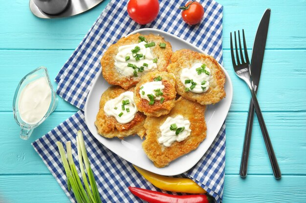 Plato con sabrosos panqueques de patata para Hanukkah y algunos ingredientes sobre una mesa de madera