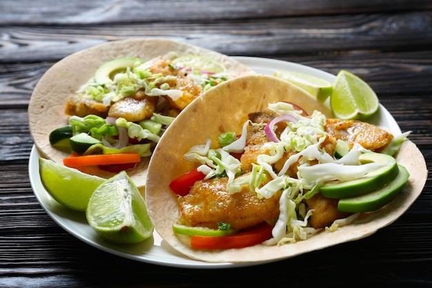 Plato con sabrosos tacos de pescado en mesa de madera