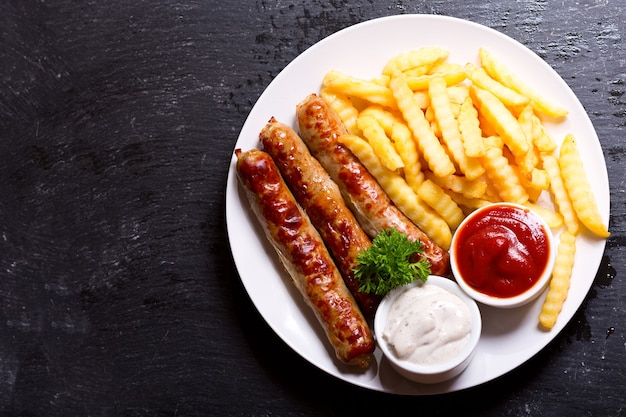 Plato de salchichas a la parrilla con papas fritas, vista superior