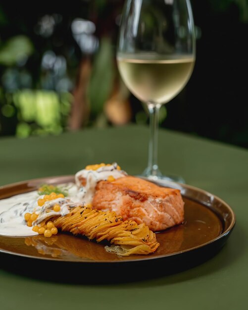 Un plato de salmón con una copa de vino blanco.