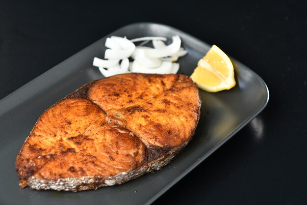 Un plato de salmón a la parrilla con rodajas de limón.