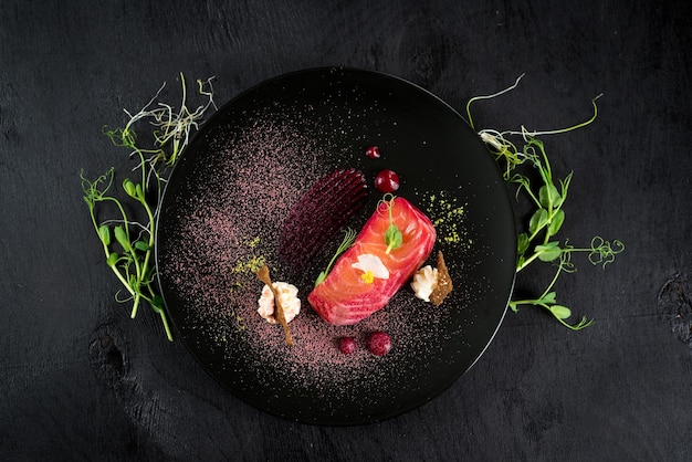 Plato de salmón de pescado rojo con salsa sobre fondo negro