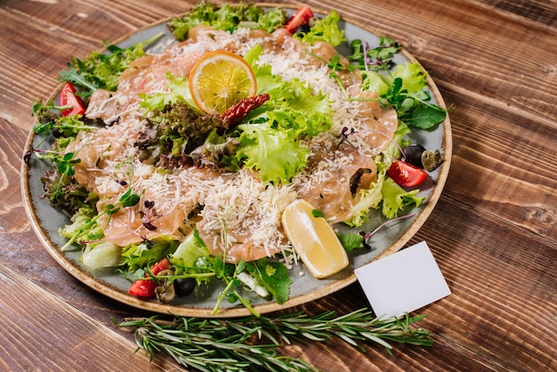 Un plato con salmón, verduras y hierbas sobre fondo de madera