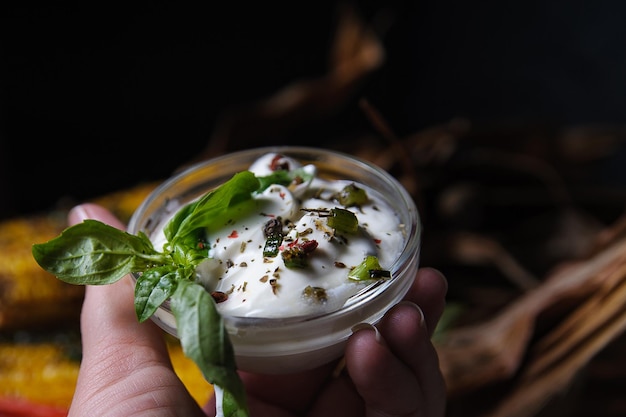 Plato con salsa blanca, especias y albahaca en las manos.