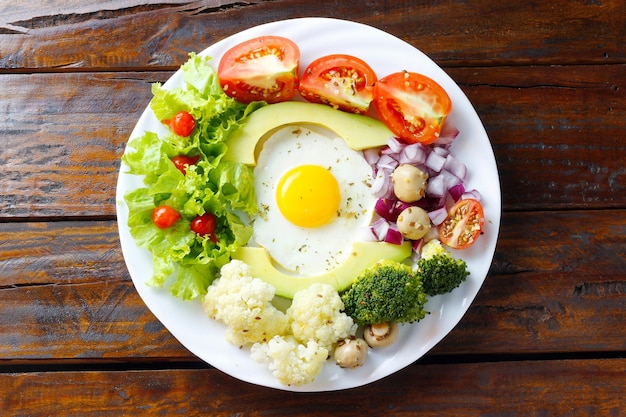 Plato saludable de ensalada de aguacate con huevos y verduras sobre una mesa rústica de madera Dieta cetogénica y paleolítica