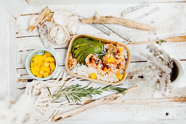 Plato saludable rico en vitaminas con arroz de camarones y aguacate en ecobox entregado por un servicio de entrega