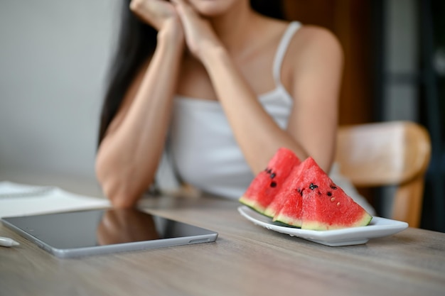 Un plato con sandías deslizantes sobre una mesa con una mujer sobrecalentada al fondo