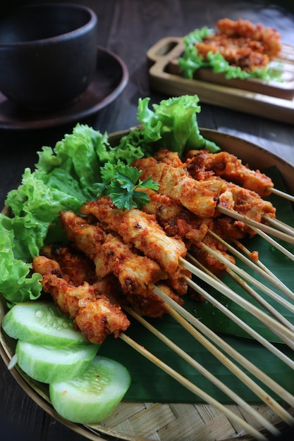 Un plato de satay de pollo con lechuga y pepino