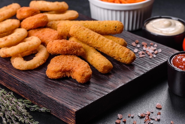 Plato de snack palitos de queso nugget de pollo aros de cebolla mezcla de snacks y salsas