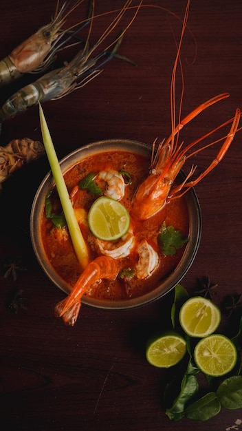 Foto un plato de sopa de camarón con limas y limas en el lado