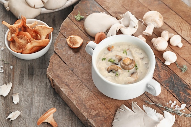 Plato con sopa de champiñones en tablero de madera