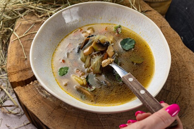 Un plato de sopa con una cucharada de pescado y verduras.