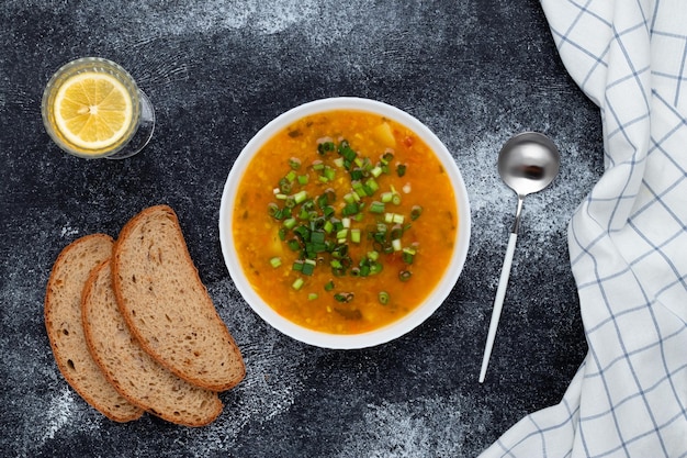 Un plato de sopa de lentejas rojas con pan en el cuadro negro. Vista superior. Fondo de comida oscura. Un plato de la cocina tradicional griega.