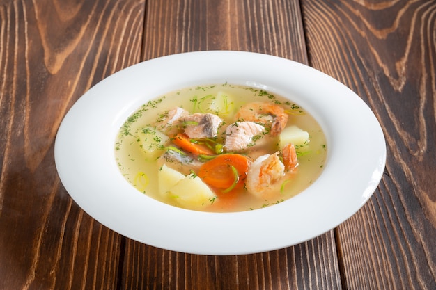 Foto plato de sopa de mariscos con gambas y salmón