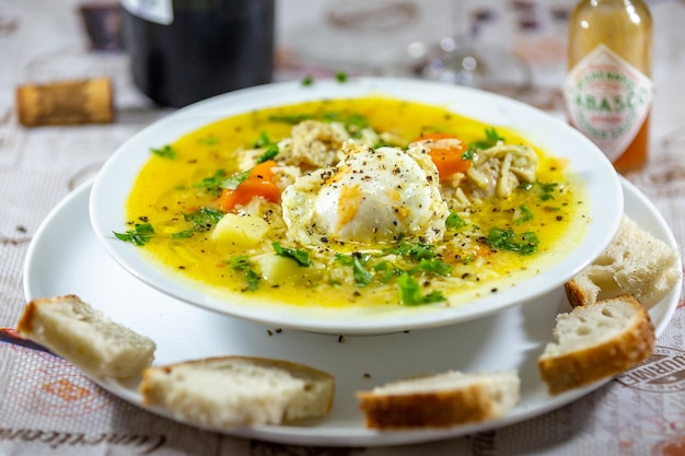 Un plato de sopa de pollo con pan al lado